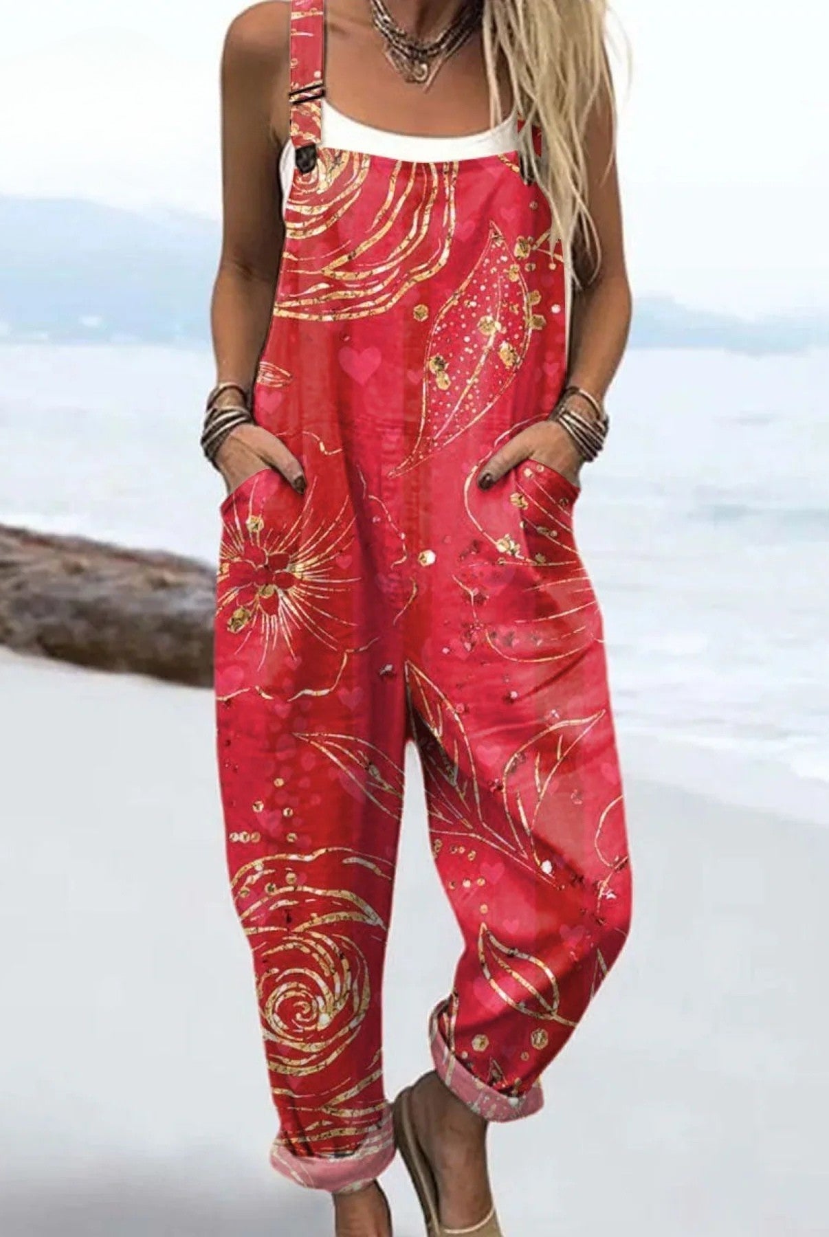 Front view of the Anya floral pattern jumpsuit in red with gold flower and swirl details, showcasing its relaxed fit and rolled cuffs.