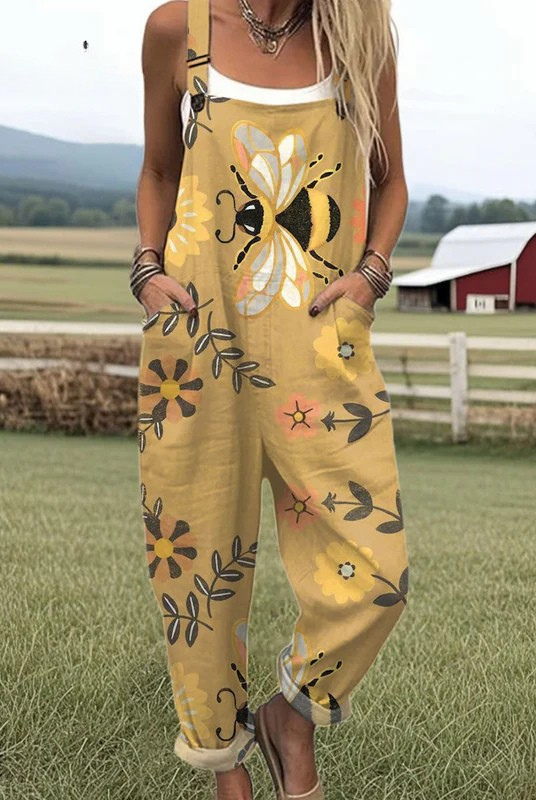 Front view of the Lumiere floral bee jumpsuit on a model, showcasing the golden yellow fabric with large whimsical bee and flower patterns, along with the deep pockets.