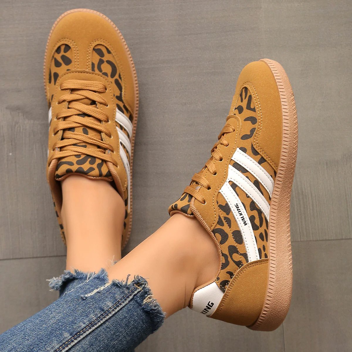 Overhead shot of feet in khaki Briony trainers, resting on a natural, light-colored surface.