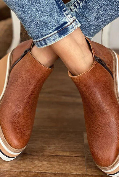 Back view of a woman walking in black Elara casual wedge ankle boots, showing the subtle heel lift.