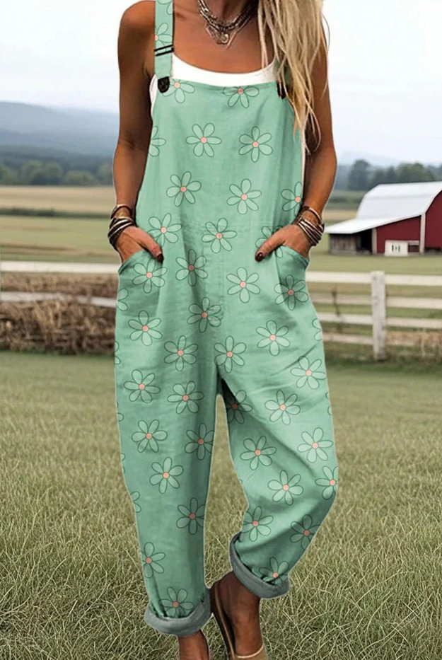 Front view of a woman wearing the mint green Elina daisy print jumpsuit, styled casually outdoors, showcasing its relaxed fit and adjustable straps.