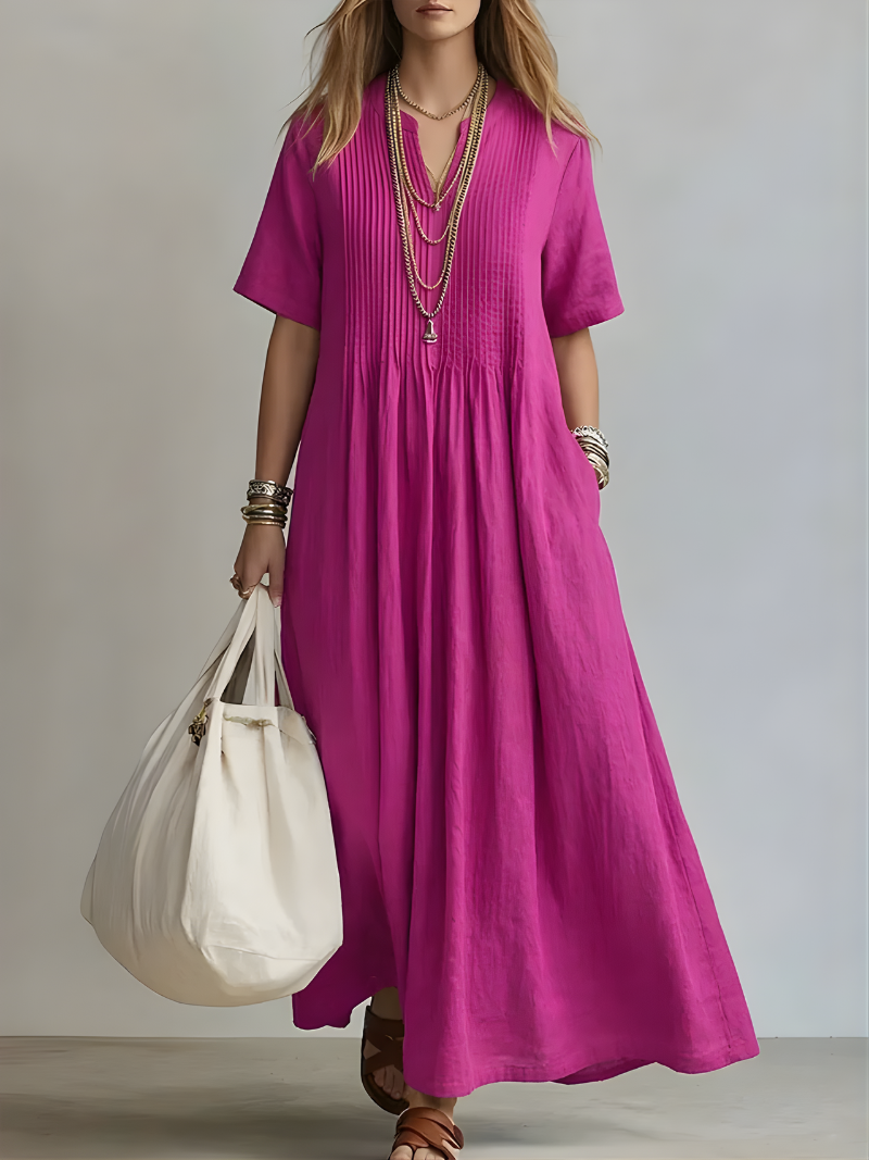 Front view of a woman wearing a vibrant pink Estelle flowing V-neck maxi dress, showcasing its elegant drape.