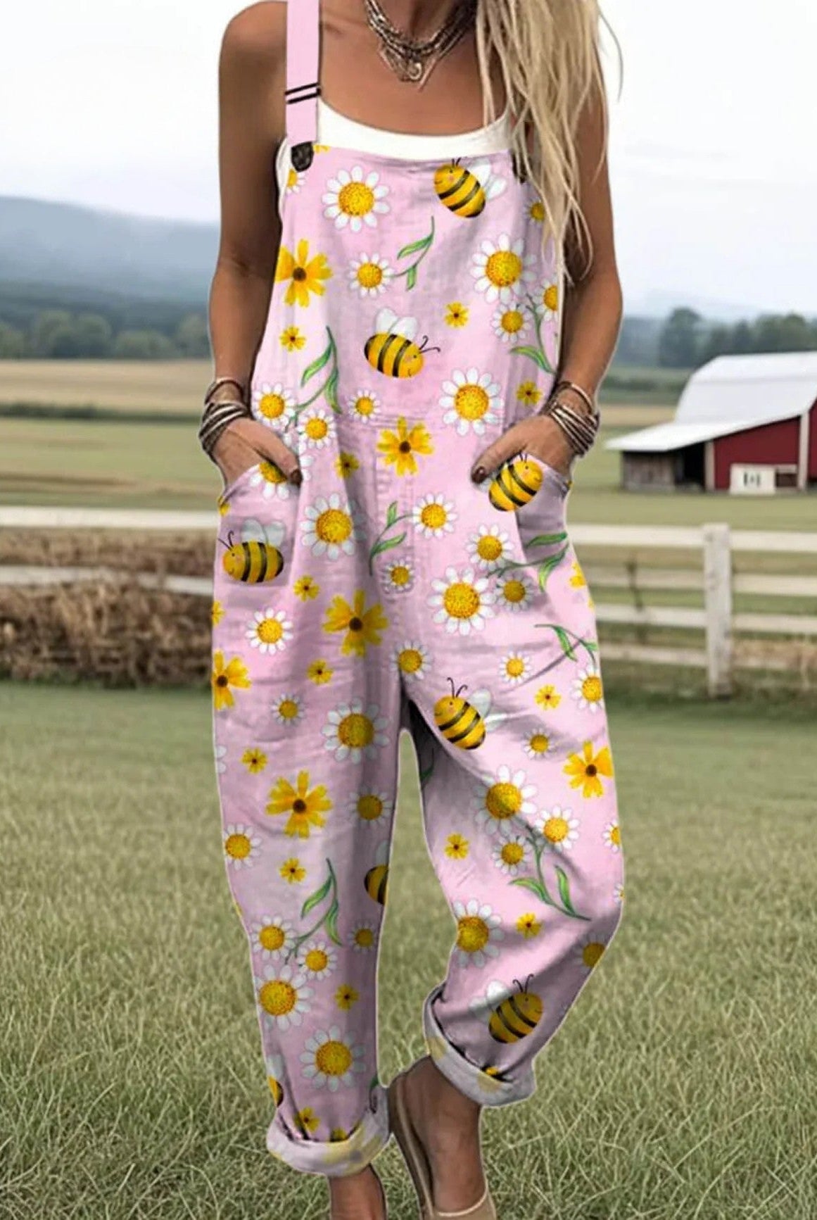 Volledige weergave van de zachtroze Fiora jumpsuit met handgeschilderde zonnebloem en bij, comfortabel vallend.