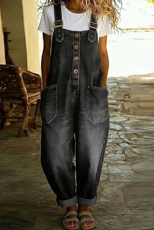 Lifestyle shot of a woman comfortably seated outdoors, wearing the Hadley soft denim overalls, illustrating ease of movement.