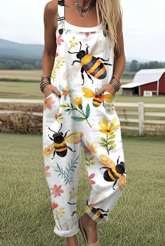 Front view of the Juniper white overall jumpsuit with a vibrant bee and blossom print, showcasing its relaxed fit and adjustable straps.
