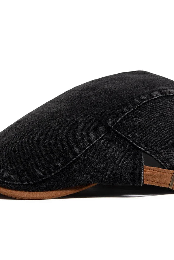 A lifestyle shot of the premium denim flat cap placed on a café table, suggesting a relaxed, urban setting.