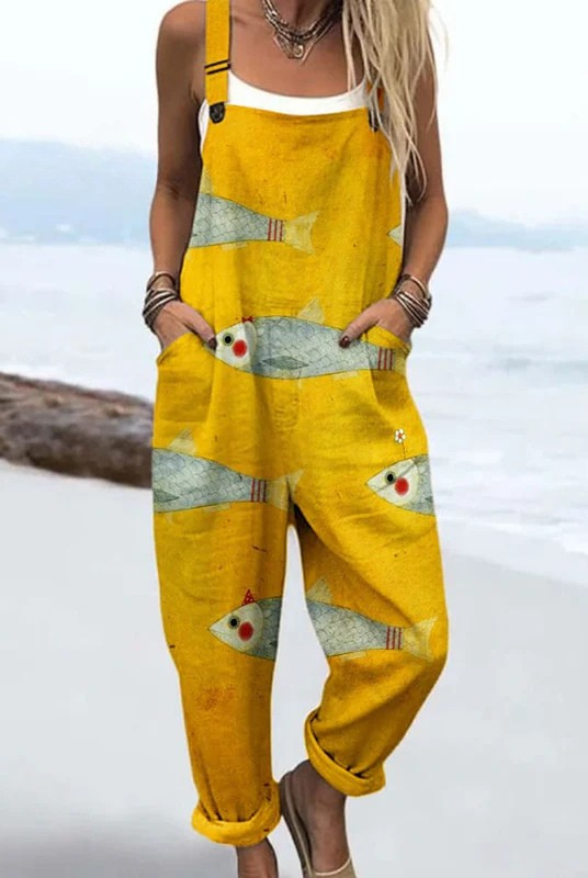 Volledige vooraanzicht van de gele strand jumpsuit met unieke visprint, gedragen door een model, in een ontspannen pose.
