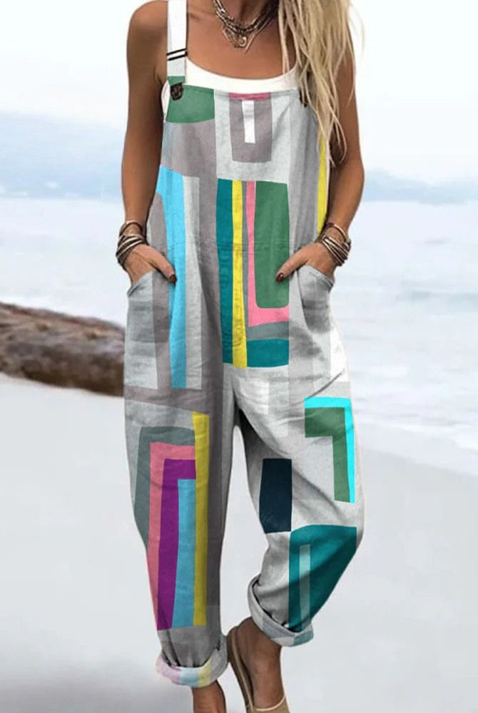 A full-body view of a woman wearing the Paloma geometric colorblock jumpsuit, showcasing its vibrant pattern and relaxed fit from a front angle.
