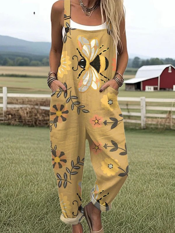 Front view of the Lumiere floral bee jumpsuit on a model, showcasing the golden yellow fabric with large whimsical bee and flower patterns, along with the deep pockets.