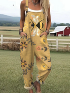 Front view of the Lumiere floral bee jumpsuit on a model, showcasing the golden yellow fabric with large whimsical bee and flower patterns, along with the deep pockets.