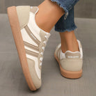 Lifestyle image of a woman wearing black orthopaedic trainers, walking outdoors on a paved path.