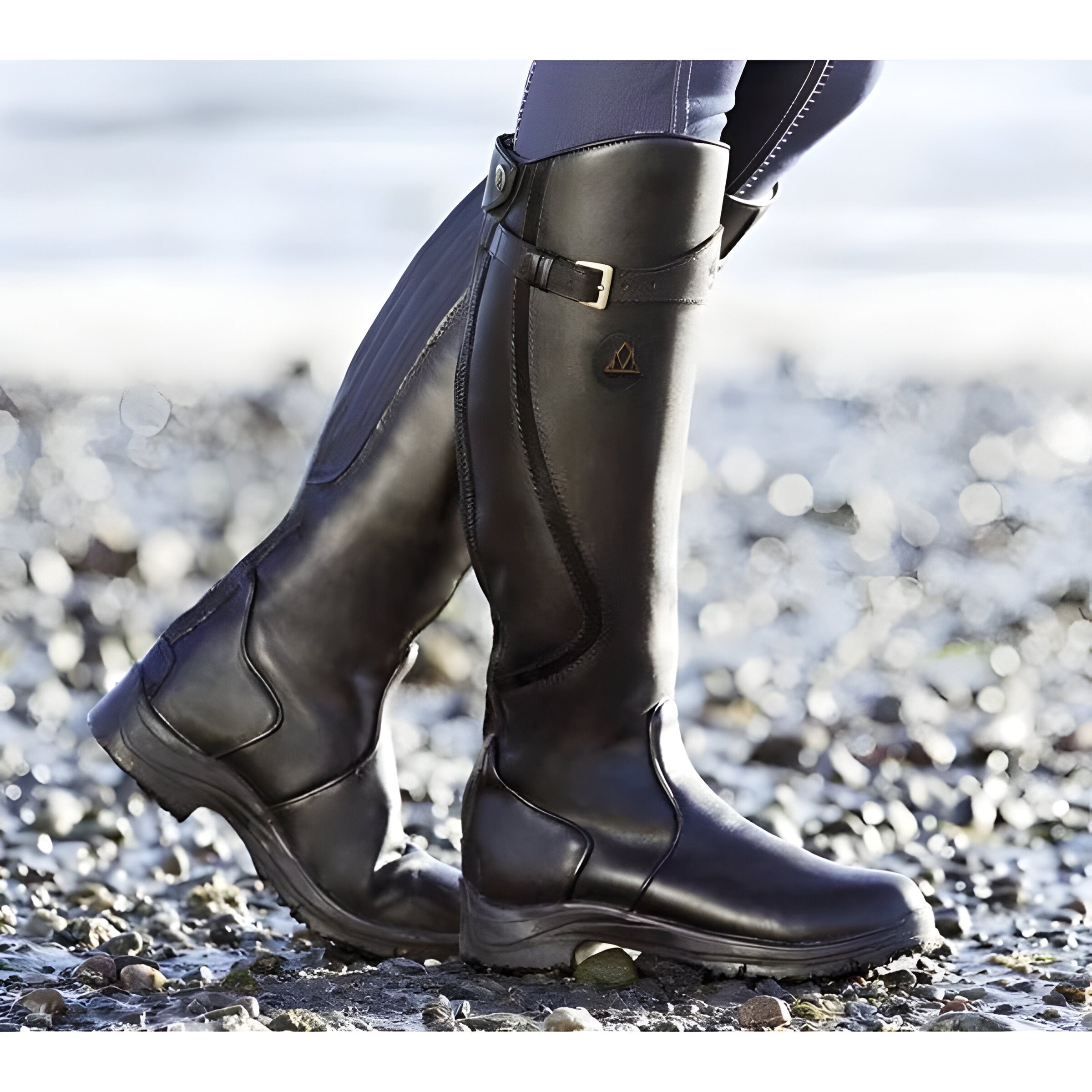 Model wearing green Calliope orthopedic leather boots while standing comfortably outdoors on a paved path.