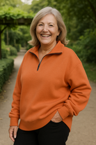 Front view of the orange Elara quarter-zip knit pullover on a model, showcasing its relaxed fit and textured fabric.