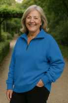 Group of various colored Elara quarter-zip knit pullovers folded neatly, showing the range of available options.