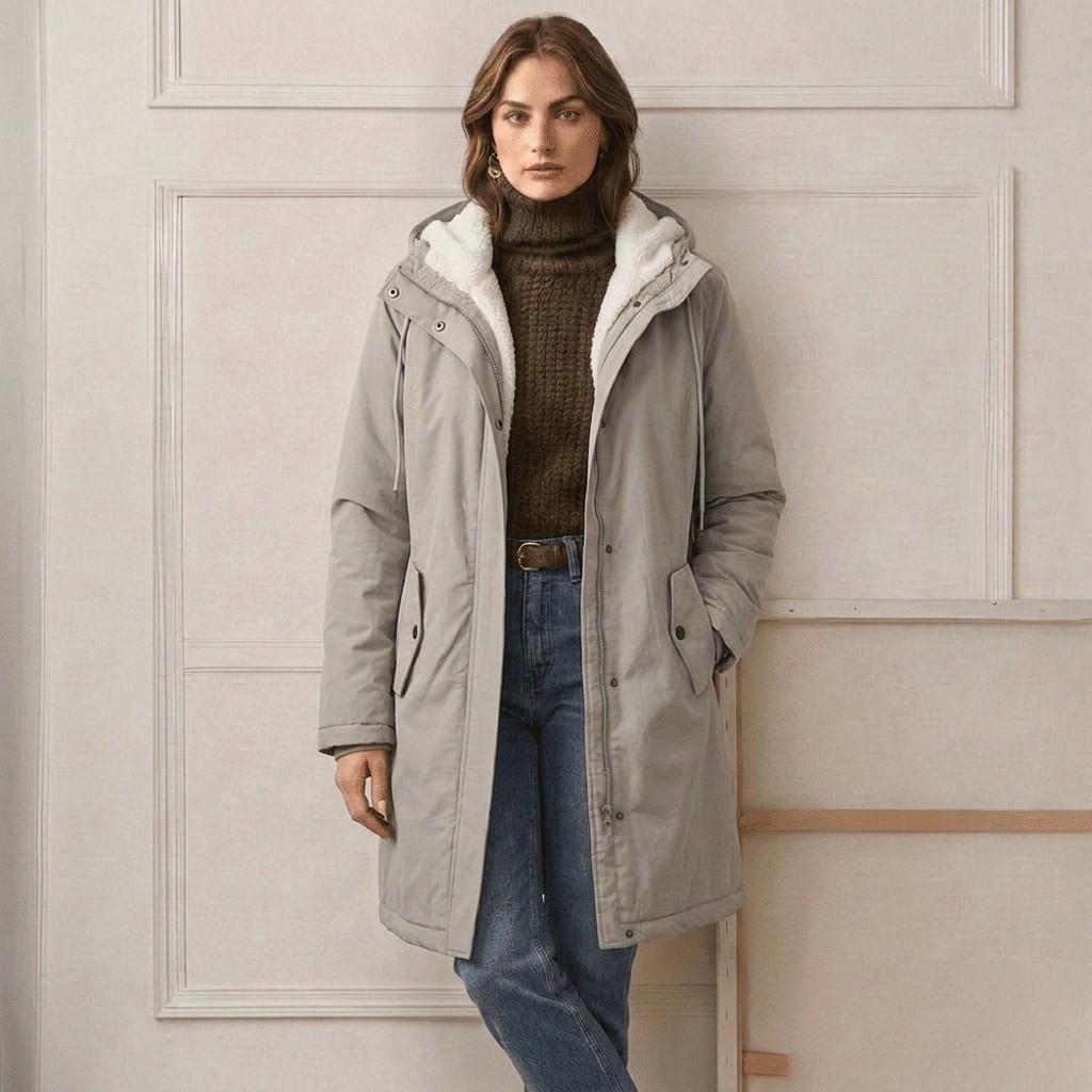 Woman zipping up the midnight navy Elara waterproof parka, emphasizing ease of use and warmth.