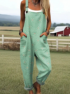 Front view of a woman wearing the mint green Elina daisy print jumpsuit, styled casually outdoors, showcasing its relaxed fit and adjustable straps.