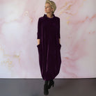 Lifestyle shot of a woman comfortably posing in a red velvet maxi dress, emphasizing its versatile style.