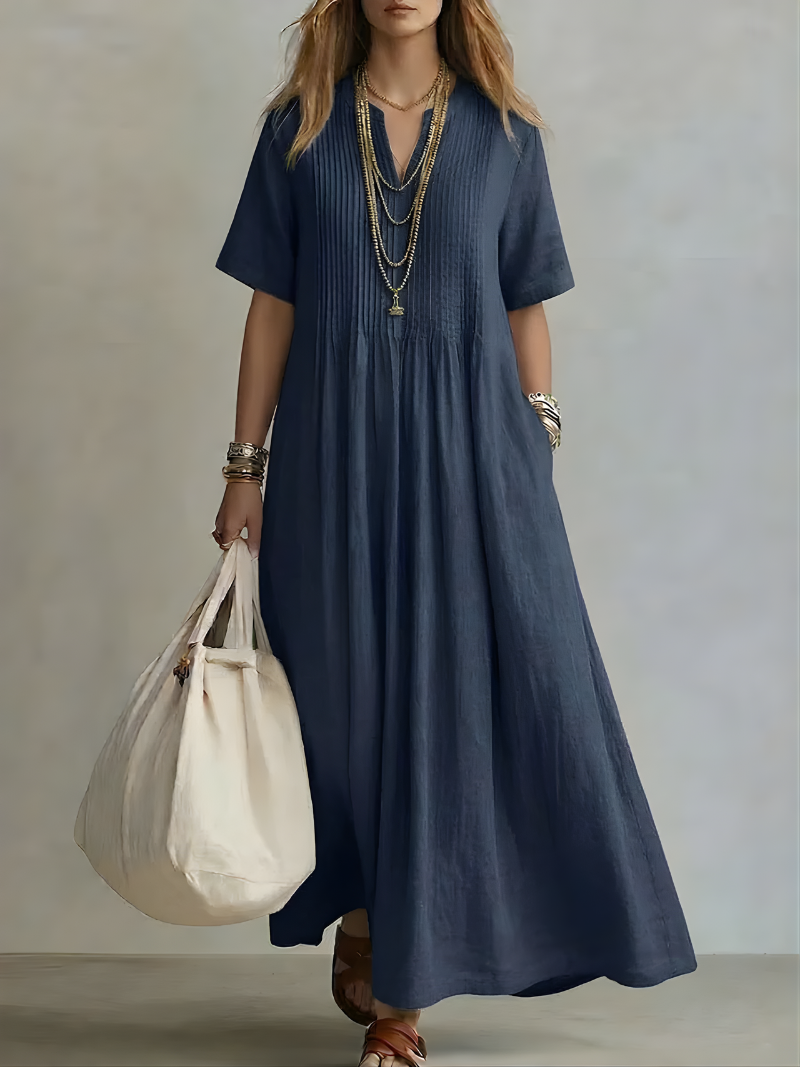 Lifestyle shot of a woman walking outdoors in a navy blue Estelle flowing V-neck maxi dress, perfect for a summer day.