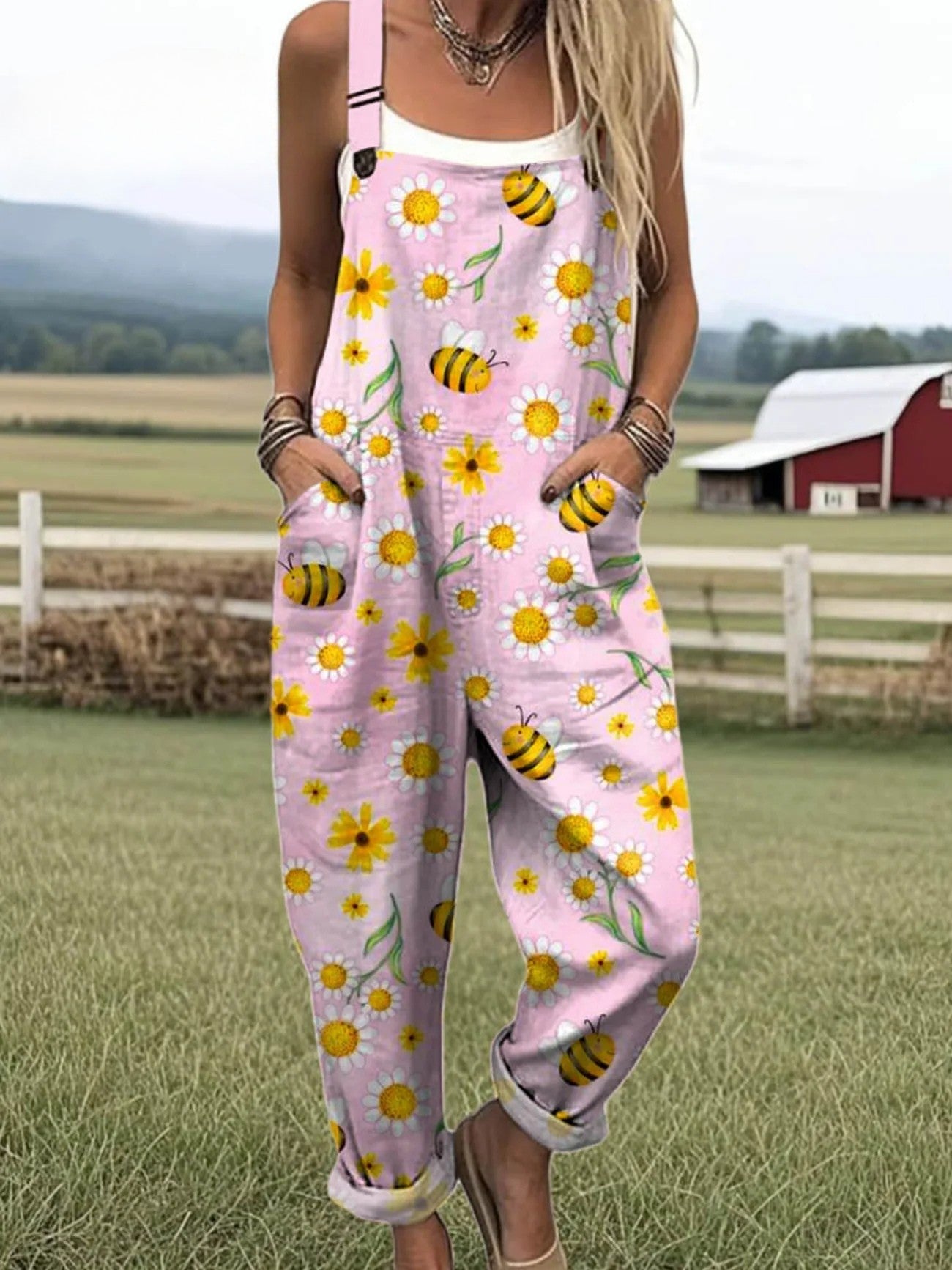Volledige weergave van de zachtroze Fiora jumpsuit met handgeschilderde zonnebloem en bij, comfortabel vallend.