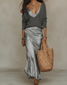 Detail of the neckline and sleeve design of the knit sweater from the two-piece ensemble.