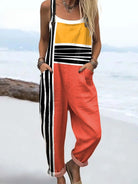 Front view of the Hadley color block jumpsuit featuring mustard yellow top, coral red mid-section, and black and white striped pants with deep pockets, worn by a model against a neutral background.