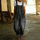 Lifestyle shot of a woman comfortably seated outdoors, wearing the Hadley soft denim overalls, illustrating ease of movement.