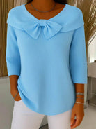 Front view of the Isolde elegant knitted top in blue, showcasing the delicate bow detail and soft texture.