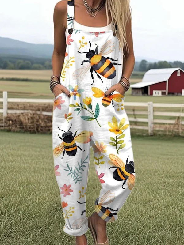 Front view of the Juniper white overall jumpsuit with a vibrant bee and blossom print, showcasing its relaxed fit and adjustable straps.
