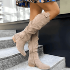 A woman wearing stylish dark green Kalina knee-high suede boots with a neutral-toned dress, showcasing the full length.