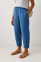 Model wearing Kallista linen-cotton blend trousers in a vibrant blue, styled for a casual outdoor setting.