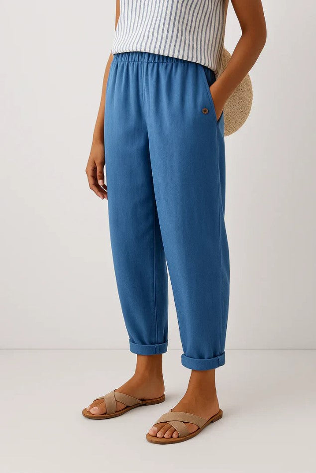 Model wearing Kallista linen-cotton blend trousers in a vibrant blue, styled for a casual outdoor setting.