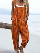 Front view of a woman wearing the Kiana artistic line jumpsuit, showcasing its burnt orange color and abstract pattern with wide-leg design.