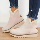 Woman wearing beige Kira orthopedic ankle boots, walking outdoors on a paved path, showing full body.