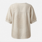 Overhead flat lay of the Calliope embroidered casual top, emphasizing the fabric quality and unique button placket.