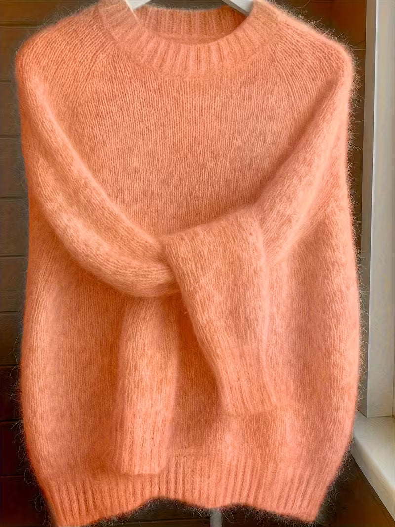 Lifestyle image of a woman enjoying a cup of coffee while wearing the orange Lila cashmere-blend sweater.