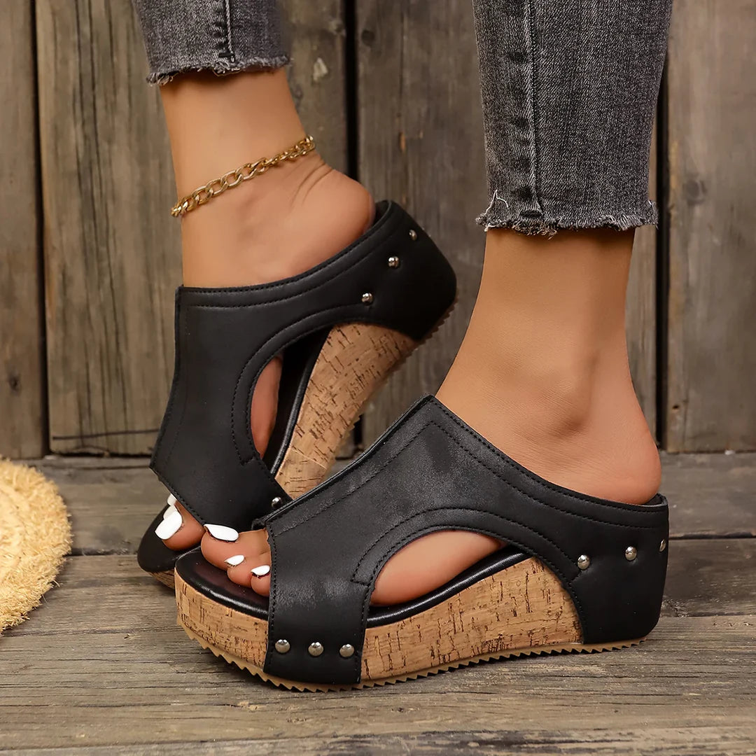 A pair of black Marlowe studded wedge sandals, shown from a direct side profile, highlighting the elegant wedge heel and metallic stud details.