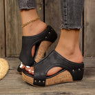 A pair of black Marlowe studded wedge sandals, shown from a direct side profile, highlighting the elegant wedge heel and metallic stud details.