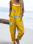 Volledige vooraanzicht van de gele strand jumpsuit met unieke visprint, gedragen door een model, in een ontspannen pose.