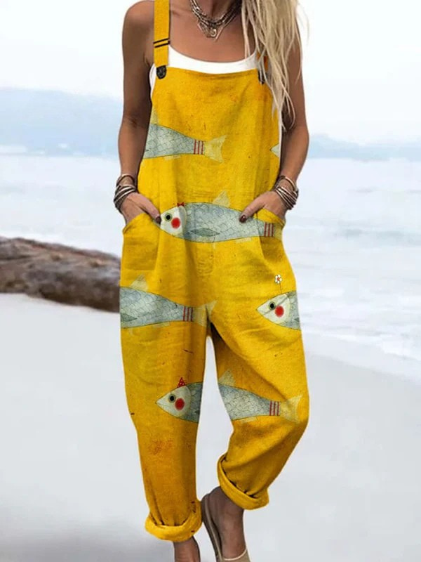 Volledige vooraanzicht van de gele strand jumpsuit met unieke visprint, gedragen door een model, in een ontspannen pose.