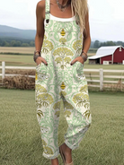 Front view of the Seraphina whimsical countryside jumpsuit, showcasing its green and gold bee and blossom print, relaxed fit, and adjustable straps.